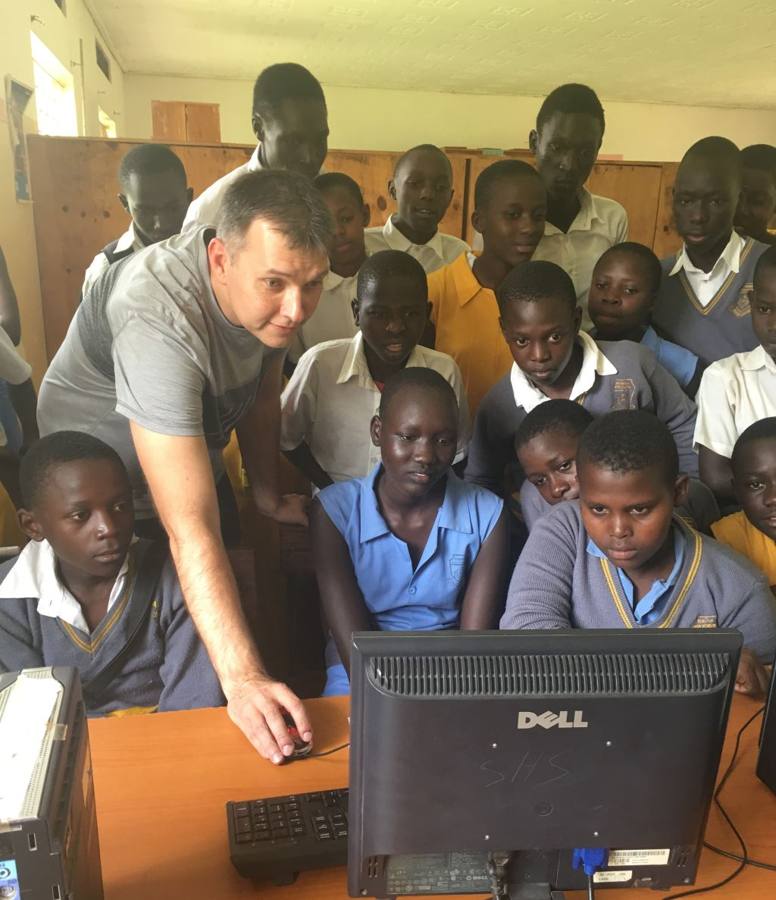 Aleksey Sinyagin showing a group of students how to use a donated desktop computer in a school in Uganda