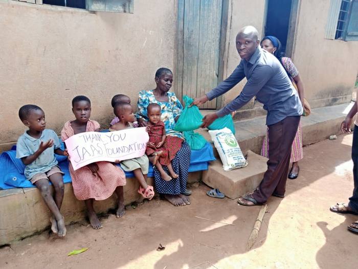 A volunteer handing bags of food to a family in Uganda during the pandemic