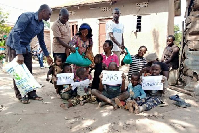 Children in Uganda holding handwritten signs thanking the JAAS Foundation after a relief delivery
